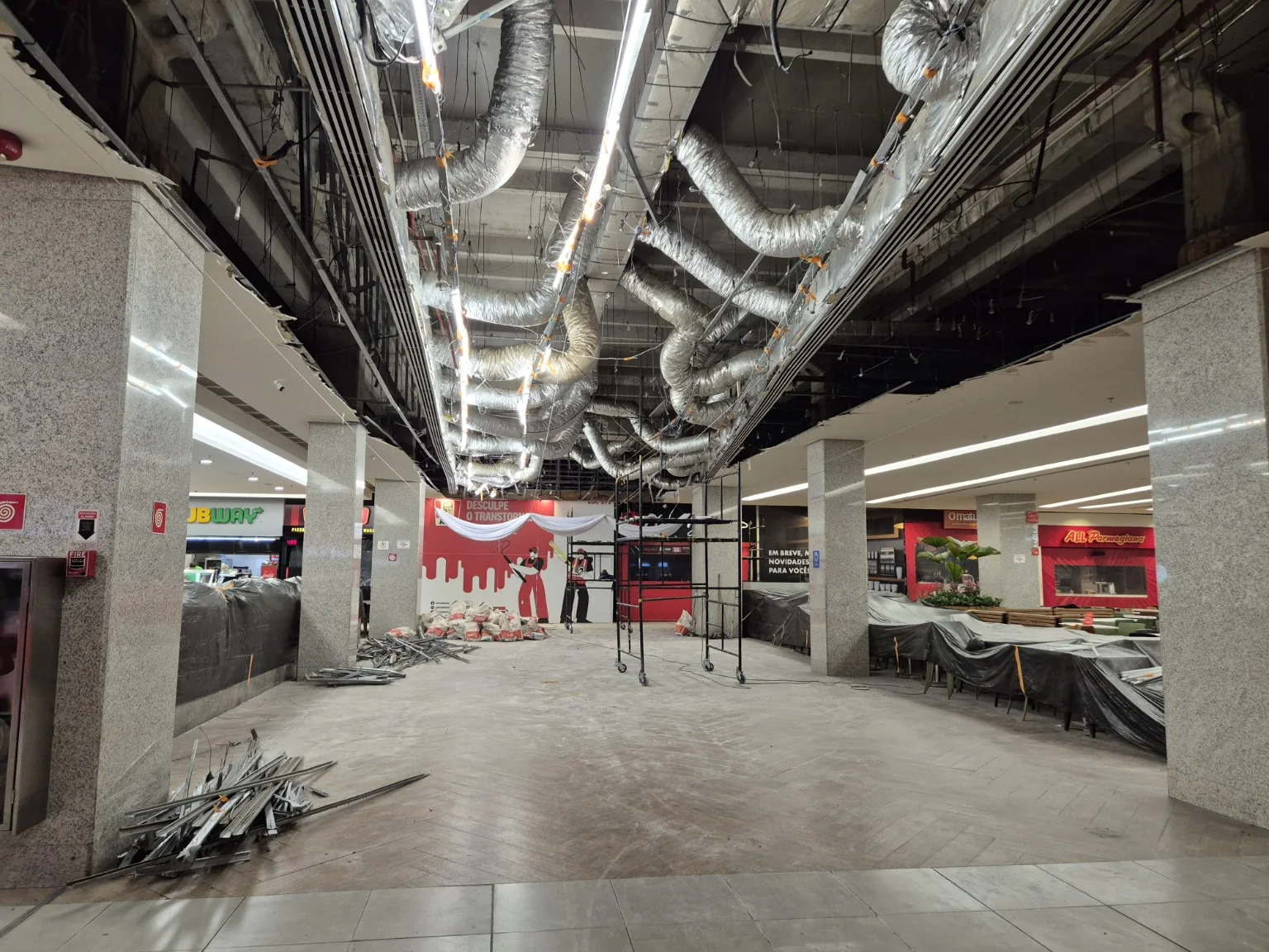 Praça de alimentação do Shopping Metrô Tatuapé durante demolição noturna, com mobiliário protegido